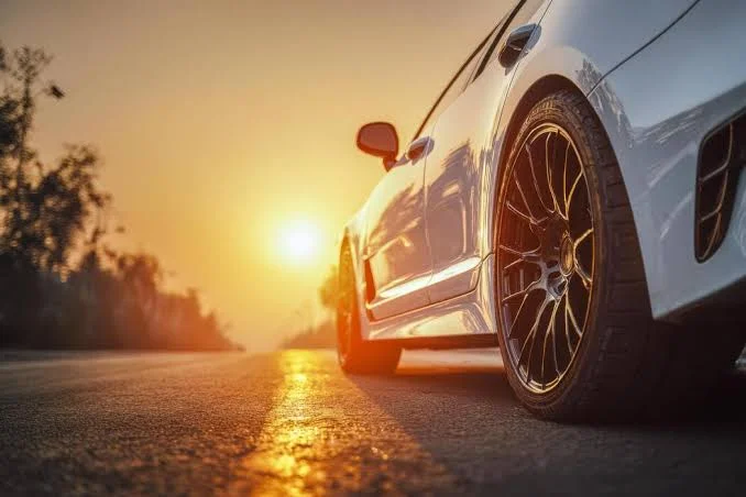Funny Tire Puns featuring a clean car on an open road with visible tires and a cheerful road trip atmosphere